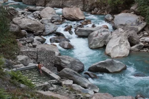 Piscina naturale con sorgenti calde e torrente di montagna roccioso e glaciale di colore turchese